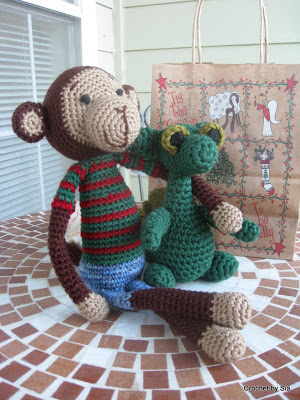 Crocheted monkey with its arm around a crocheted dragon